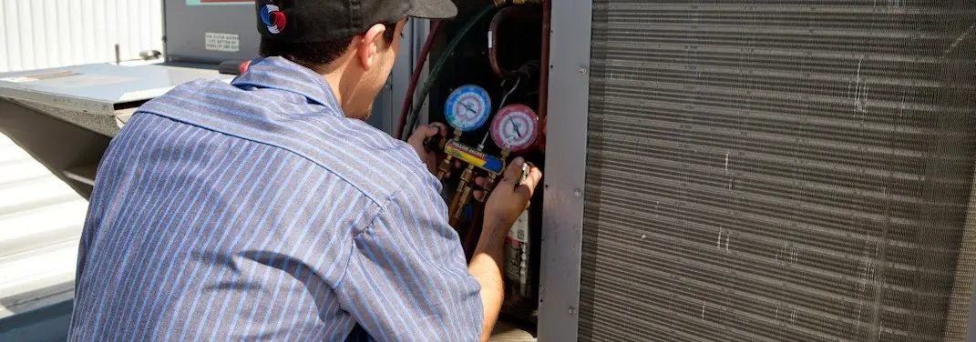 HVAC technician servicing a condenser unit in West Perrine