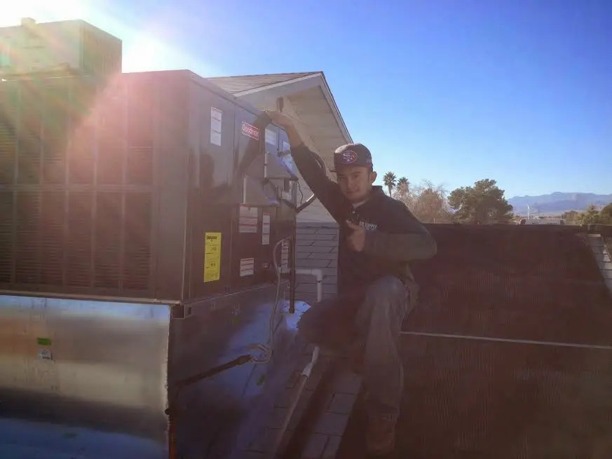 HVAC technician performing AC Tune-Up on a rooftop unit in West Perrine